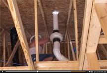 View of man installing radon system in attic of new house