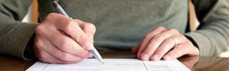 image of a person's hand holding a pen filling out a form