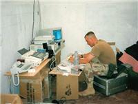 Sgt. Danny Hart, U.S. Army, 55th Signal Company (combat camera), hard at work in Mogadishu at his desk constructed of MRE boxes.